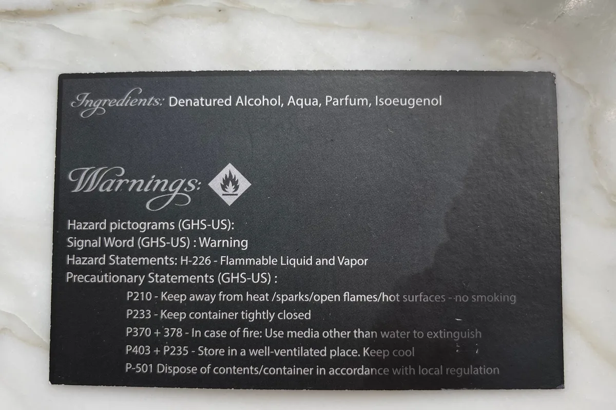 Back-of-package ingredient and warning card from a bottle of Burnt Hair, listing the ingredients as Denatured Alcohol, Aqua, Parfum, and Isoeugenol, and reproducing the EU GHS hazard statement H-226 — Flammable Liquid and Vapor — with five precautionary statements about keeping it away from heat and open flames.