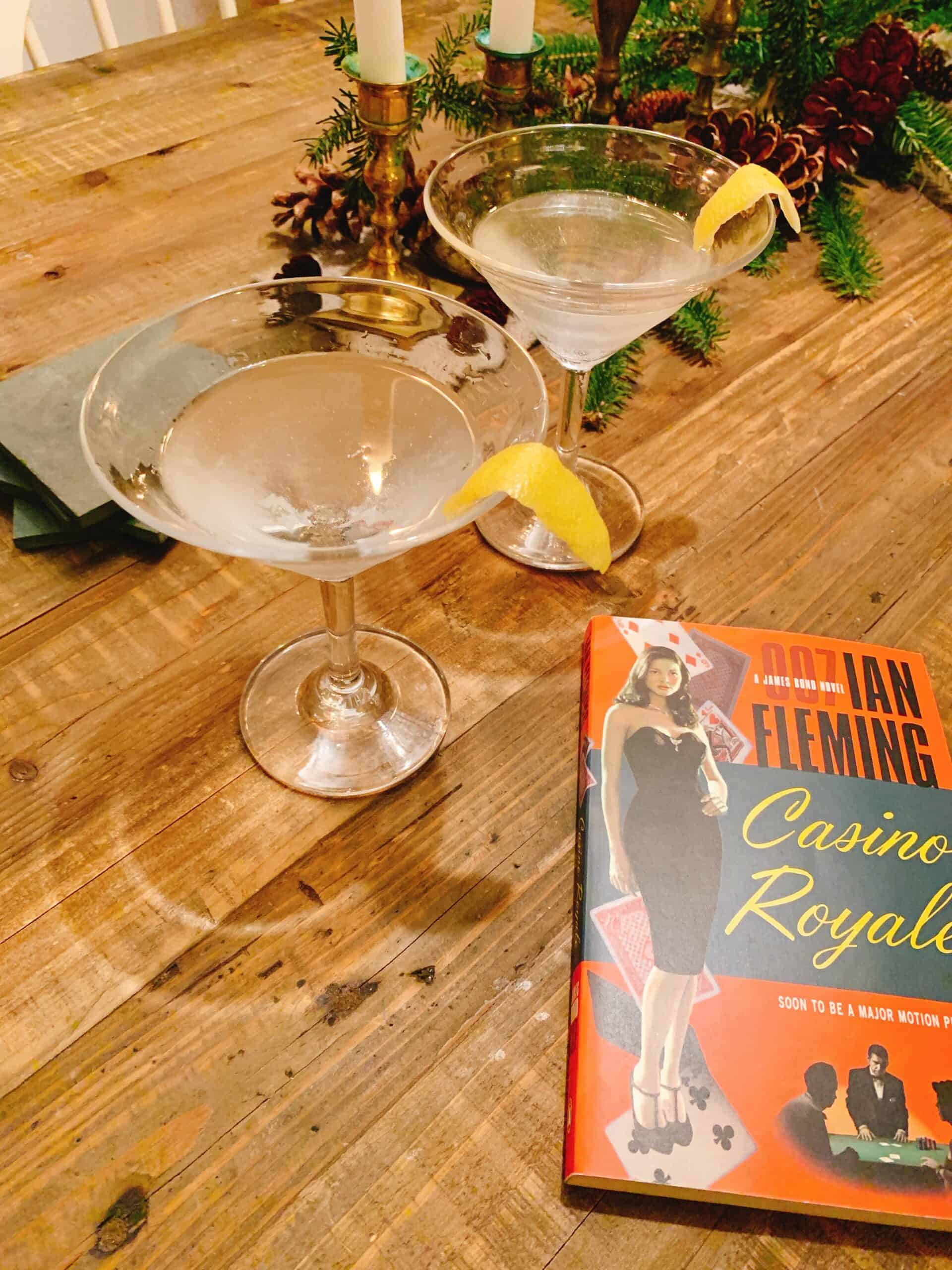 Article: What Cologne Does James Bond Wear? Image shows a copy of Casino Royale on a wooden table next to two Vesper cocktails